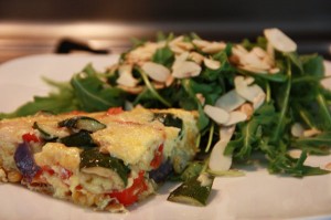 Fritatta on a plate with arugula and toasted almonds