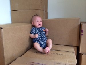 Crying baby sitting on packing boxes