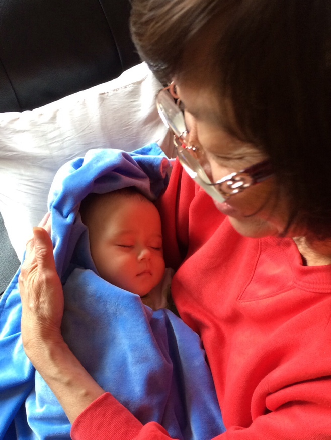 Baby in blue blanket asleep in grandmas arms