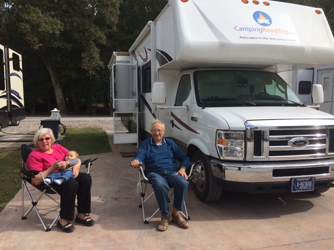 Grandma grandpa and baby sitting in front of RV