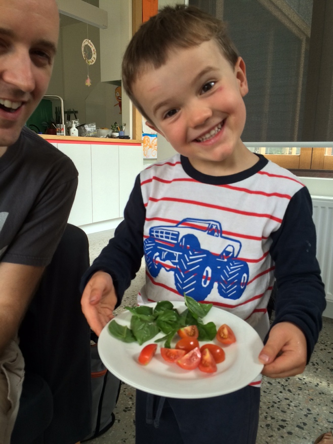 Boy holding basil and tomato dish