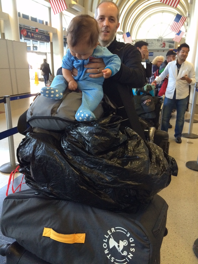 Baby boy o sitting on top of luggage