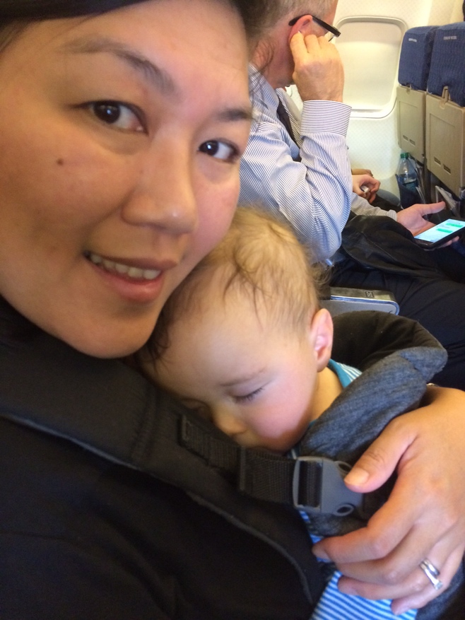 Mum carrying napping baby on plane